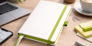 Записна книжка A5 Blanco з зеленою резинкою на робочому столі з ноутбуком та кавою