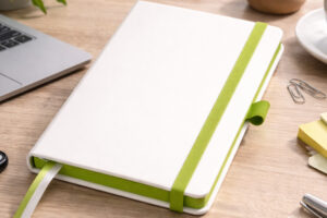 Записна книжка A5 Blanco з зеленою резинкою на робочому столі з ноутбуком та кавою