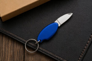 Брелок для ключів Drop TM Discover з металевим лезом на темній поверхні, синій корпус