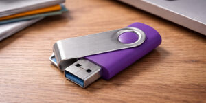 Металева флешка GOODRAM USB TS001 Twister у відкритому вигляді на дерев’яному столі поруч із ноутбуком