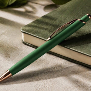 Ручка кулькова металева Diamond темно-зелена з золотими деталями на столі поруч із блокнотом