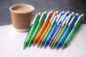 Ручка кулькова пластикова New York поруч із стаканом кави, набір з 15 рекламних ручок як альтернатива вартості кави