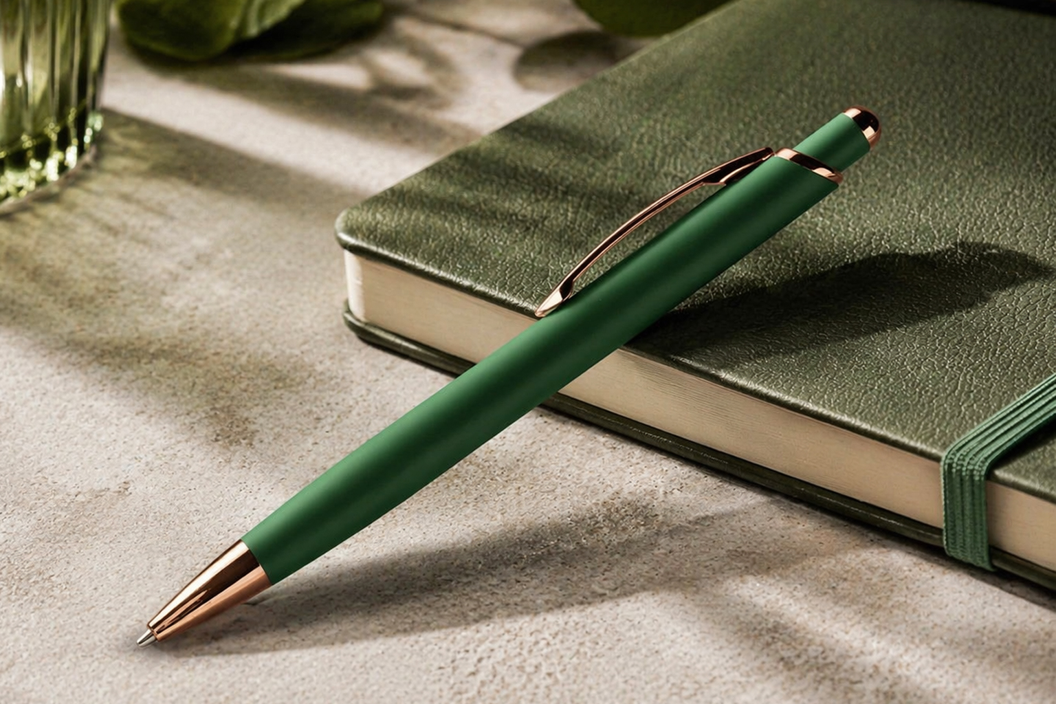 Ручка кулькова металева Diamond темно-зелена з золотими деталями на столі поруч із блокнотом